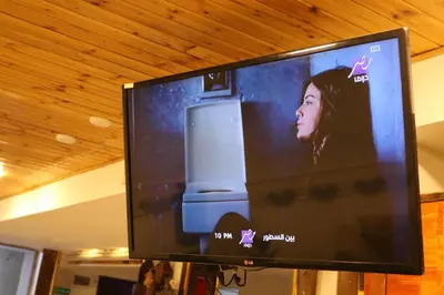 a flat screen tv with a woman on it at PetraEcho lodge Section B Home in Wadi Musa