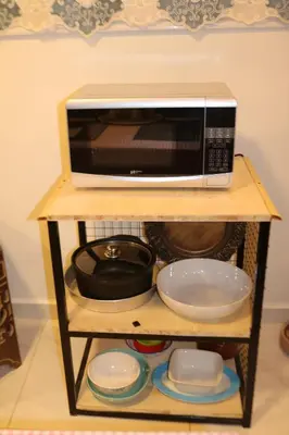 a microwave on a shelf with plates and bowls at PetraEcho lodge Section B Home in Wadi Musa