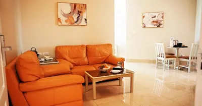 a living room with an orange couch and a table at Amman West Luxury Hotel By Azar in Amman