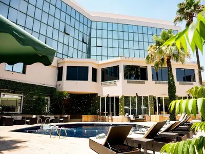 a hotel with a swimming pool and lounge chairs in front of a building at Amman West Luxury Hotel By Azar in Amman