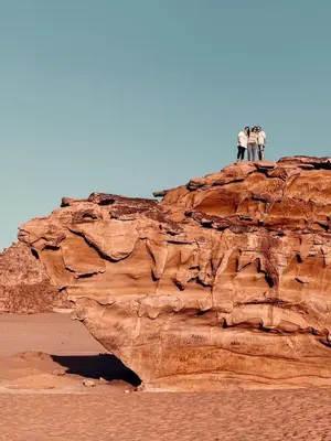 three people standing on top of a rock in the desert at Horizon Star Golden Camp in Wadi Rum