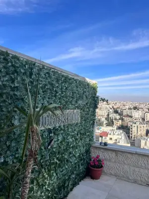 a green wall with a sign on the side of a building at Doctor roof in Amman