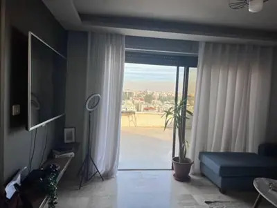 a living room with a blue couch and a large window at Doctor roof in Amman
