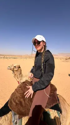 a woman riding a camel in the desert at SILENT SKY lUXURY CAMP in Wadi Rum