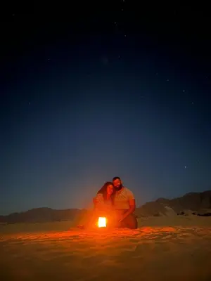 a man and woman sitting in the desert with a candle at SILENT SKY lUXURY CAMP in Wadi Rum