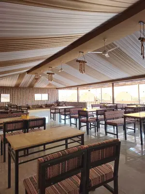 a dining hall with tables and benches and windows at SILENT SKY lUXURY CAMP in Wadi Rum
