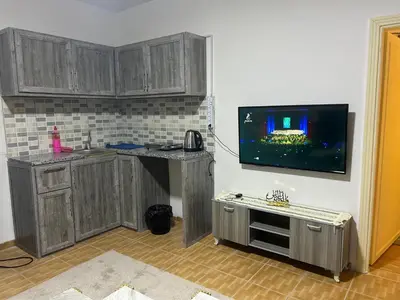a kitchen with wooden cabinets and a tv on the wall at A double bed apartment in heart of Amman شارع سلطان الهند خلف ش عبدالله غوشه in Amman