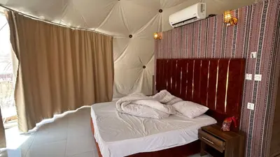 a small bedroom with a bed with a canopy at RUM AlLIRA lUXURY CAMP in Wadi Rum