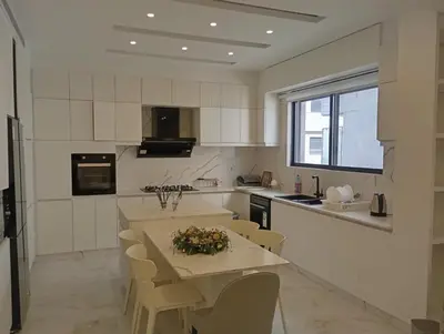 a white kitchen with a table and chairs in it at شقه مفروشه in Amman