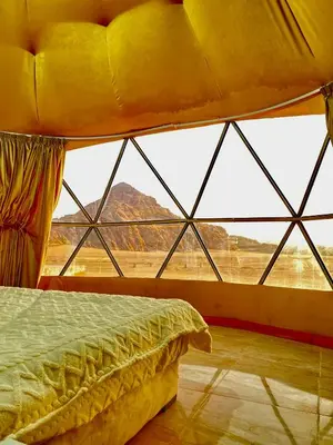 a bed in a room with a large window at moon and sky camp in Wadi Rum