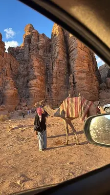 a person walking a camel in the desert at Al-Najm Coastal Camp Rum in Wadi Rum