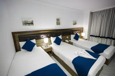 a hotel room with two beds with blue pillows at Corner View Hotel in Wadi Musa