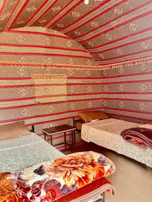 a room with two beds and a striped wall at Wadi Rum Bedouin Life in Wadi Rum