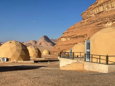 a row of domes in a desert with mountains at SARH lUXURY CAMP in Wadi Rum