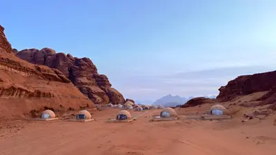 a group of domes in the desert near some rocks at SARH lUXURY CAMP in Wadi Rum