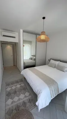 a bedroom with a large white bed and a mirror at Luxury apartments in Ayla in Aqaba