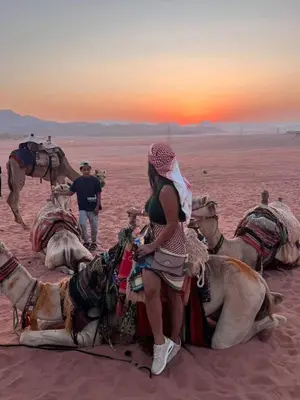 a woman riding a camel in the desert at mountains wadi rum in Disah