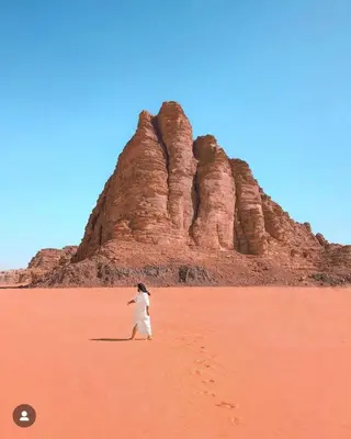 a person walking in the desert with a rock formation at Rum Magic Bubbles in Wadi Rum