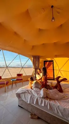 two women laying on a bed in a tent at Moon Red Bubbles Camp in Wadi Rum