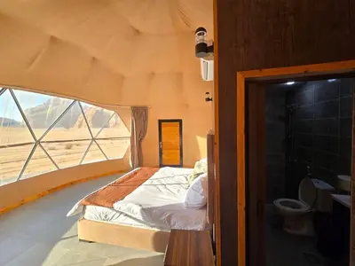 a bed in a room with a large window at Amira Luxury Camp in Wadi Rum