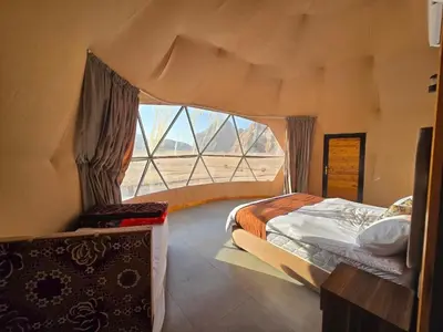 a bedroom with a bed and a large window at Amira Luxury Camp in Wadi Rum