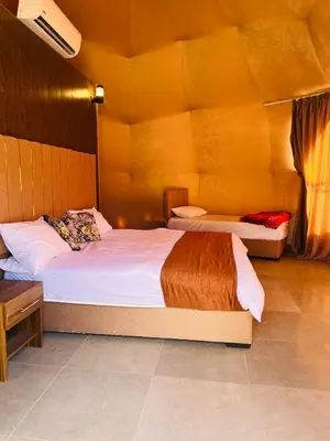 a bedroom with two beds and a desk at Amira Luxury Camp in Wadi Rum