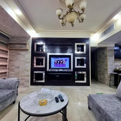 a living room with a tv and a couch and a table at Deir Ghbar Suite in Amman