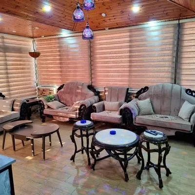 a living room with two couches and tables and chairs at Deir Ghbar Suite in Amman