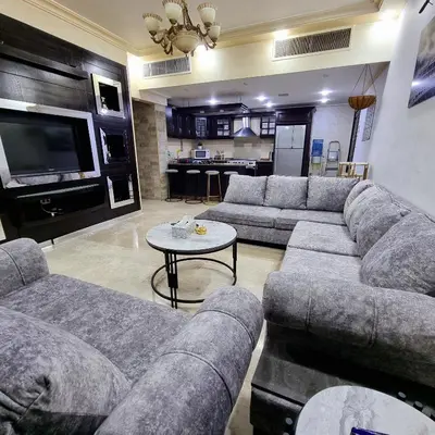 a large living room with couches and a tv at Deir Ghbar Suite in Amman