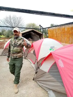 a man is standing next to two umbrellas at اربد ام قيس طريق درب الاردن in Um Qeis