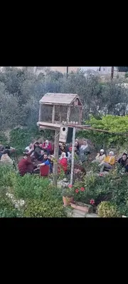 a group of people sitting around in a garden at اربد ام قيس طريق درب الاردن in Um Qeis