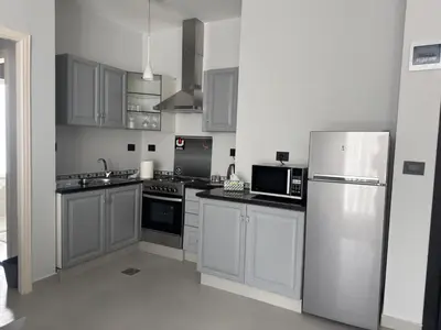 a kitchen with white cabinets and a stainless steel refrigerator at Roof 99 in Amman