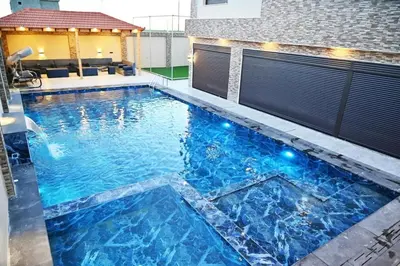 a pool with blue water in a house at For daily, weekly monthly and yearly stays in Amman