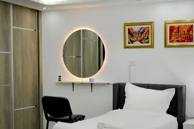 a bedroom with a mirror and a bed and a chair at Rose In Apartment in Wadi Musa