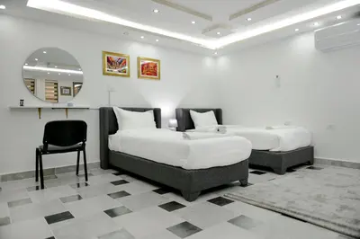 two beds in a room with a mirror and a chair at Rose In Apartment in Wadi Musa
