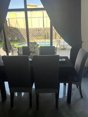 a dining room with a table and chairs and a pool at Ohio villa in Sowayma