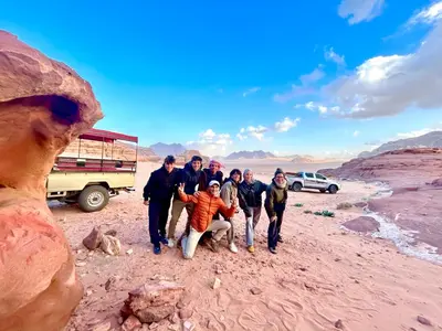 a group of people posing for a picture in the desert at Bedouin Secret Cave in Wadi Rum