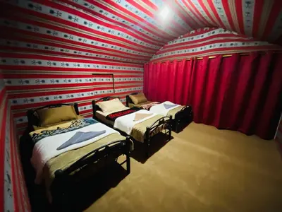 three beds in a room with red walls and red curtains at Desert Key Camp in Wadi Rum