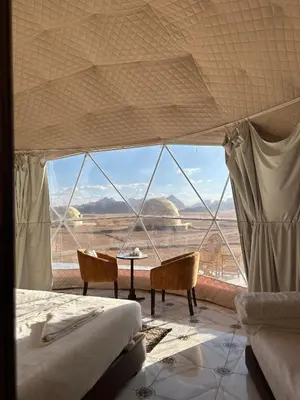 a bedroom with a bed and a view of the desert at RUM HORIZON BUBBlE LUXURY CAMP in Wadi Rum