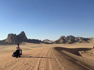 a woman and a child walking through the desert at Sleeping amidst the natural beauty of Wadi Rum, and living like a Bedouin in Aqaba