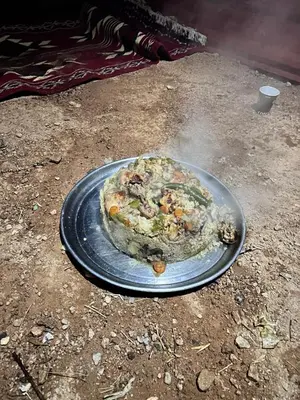 a pizza sitting on a plate on the ground at Sleeping amidst the natural beauty of Wadi Rum, and living like a Bedouin in Aqaba