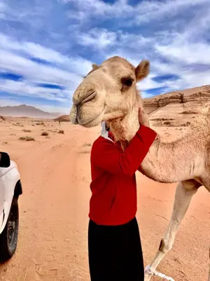a person standing next to a camel in the desert at Rum Horizon Camp& Tours in Wadi Rum