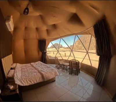 a bedroom with a bed and a large window at Rum Horizon Camp& Tours in Wadi Rum