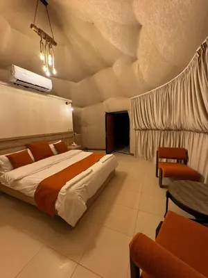 a bedroom with a bed and a table and chairs at Rum Horizon Camp& Tours in Wadi Rum