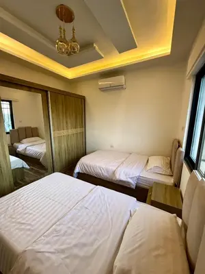 a bedroom with two beds and a chandelier at Sports city 2bd room in Amman