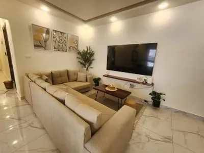 a living room with a couch and a flat screen tv at Cozy Appartment In Shmessani in Amman
