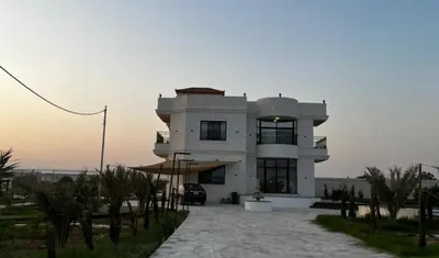 a large white building with a sunset in the background at Rest Sea Chaliet & Farm