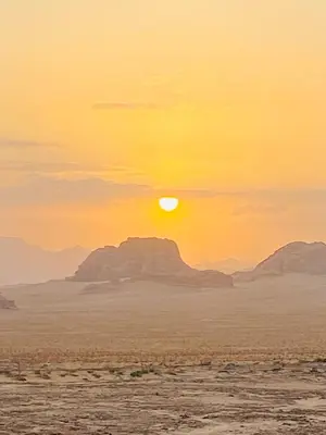 a sunset in the desert with mountains in the background at سفينة الصحراء وادي رم in Disah