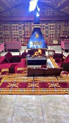 a large room with a fireplace and red chairs at سفينة الصحراء وادي رم in Disah