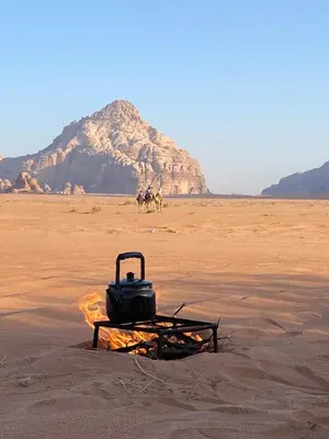 a grill on the beach with people riding horses in the desert at سفينة الصحراء وادي رم in Disah